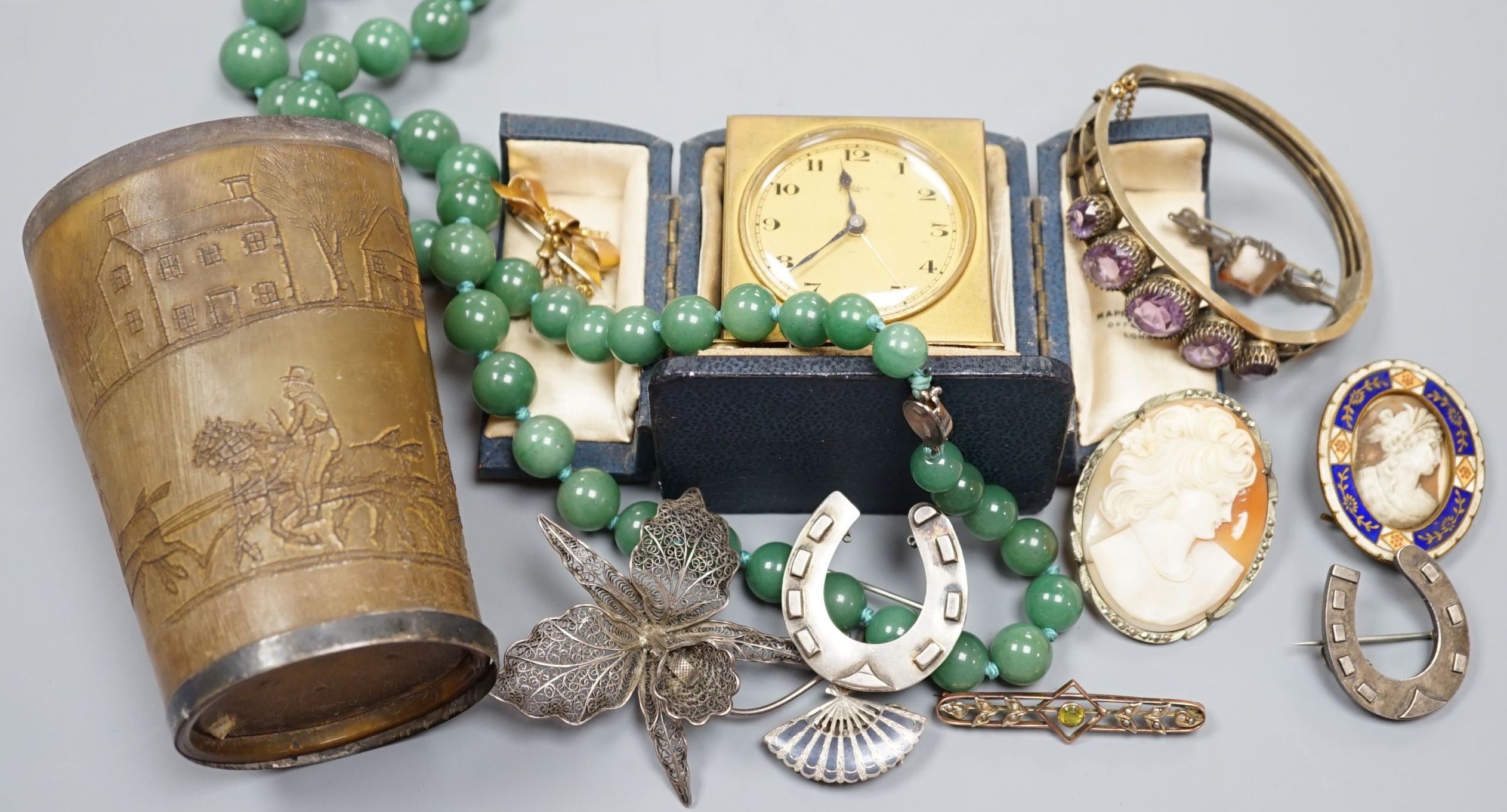 A small collection of jewellery including a silver horseshoe brooch, 9ct suspension brooch, gross 2.8 grams, and a travelling bedside timepiece and beaker.